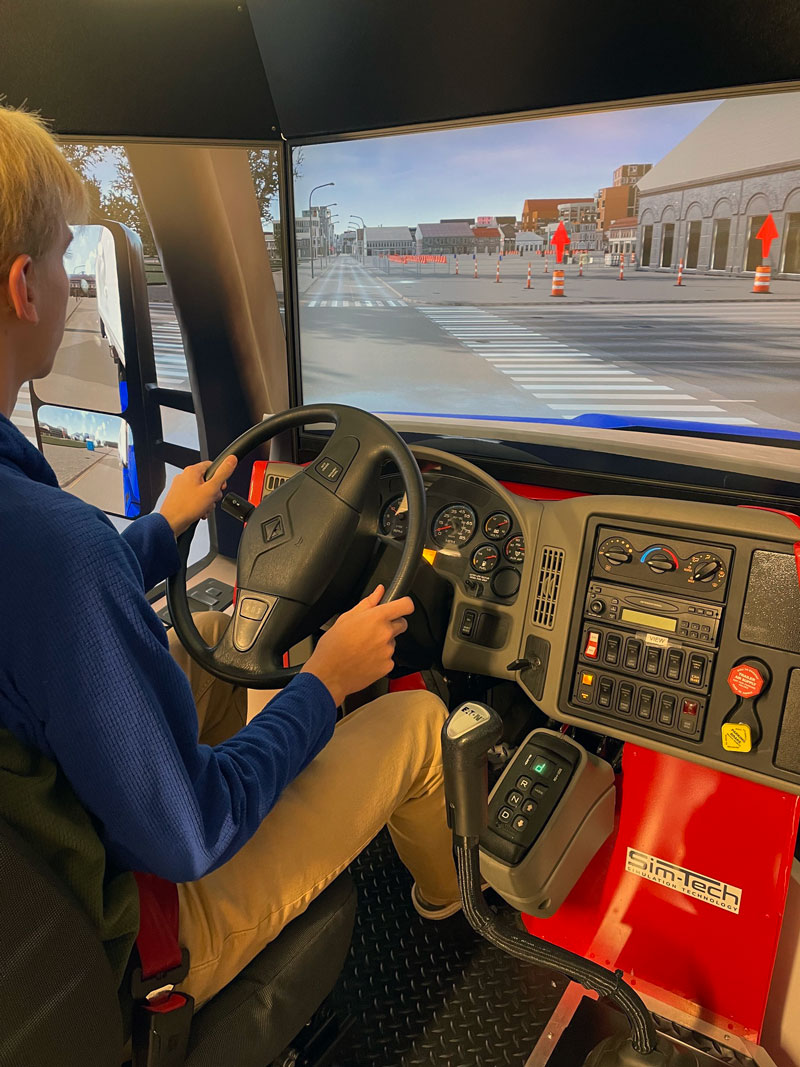 photo of a person using the CDL simulator with steering wheel and controls
