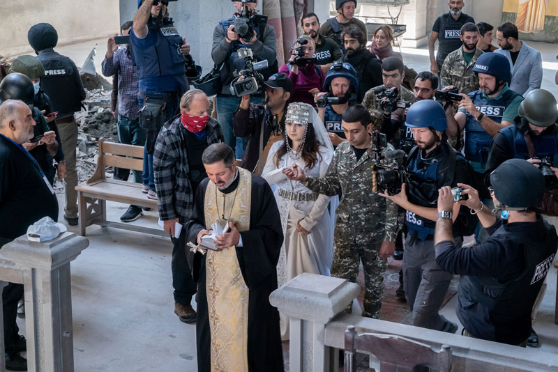 Photo of a couple getting married in a church surrounded by press in bullet proof vests.