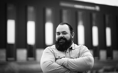 photo of Adam Messenger with his arms crossed in front of the business building on the LCCC campus