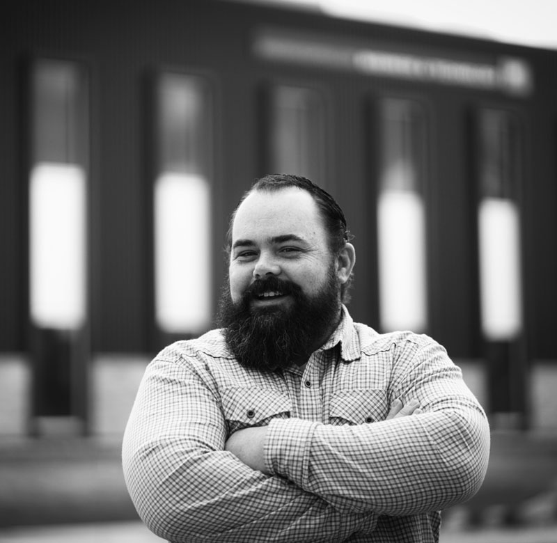 photo of Adam Messenger as student at LCCC standing in front of the Business building with his arms crossed.