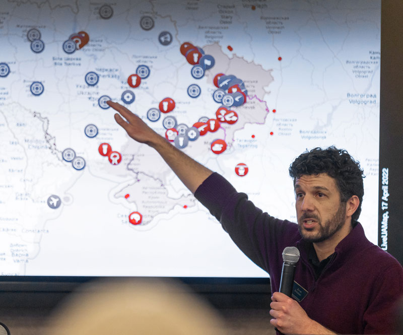 photo of Ezras Tellalian on campus giving a talk about the war in Ukraine. He's standing in from of a screen with a map of Ukraine and holding a microphone.