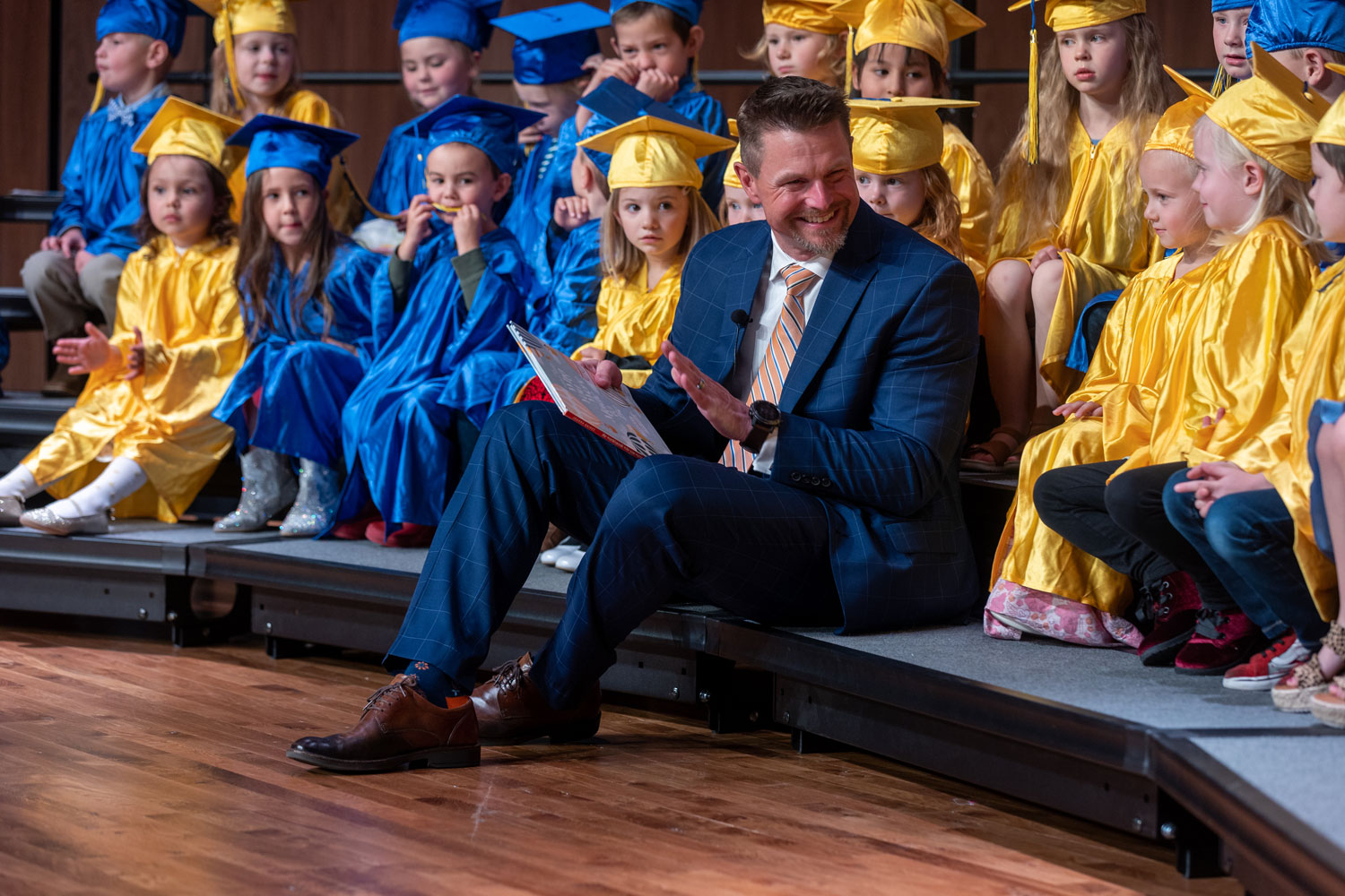 Dr. Schaffer sitting with the Children's Discovery Center graduates reading a book.