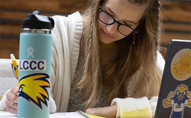 photo of student studying with laptop, notebook and waterbottle