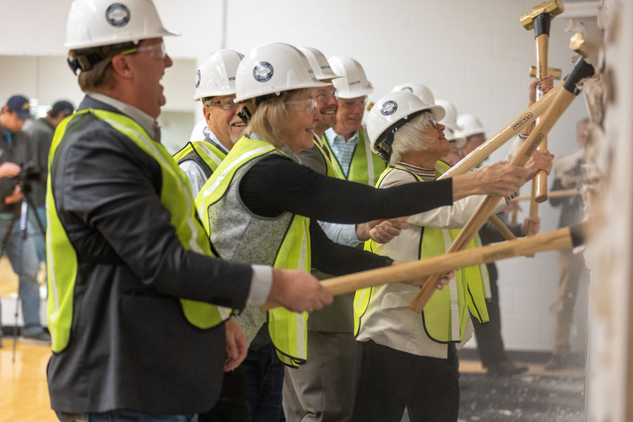 Laramie County Community College President Joe Schaffer, the Board of Trustees and and special guests break ground – or in this case drywall – with gold sledge hammers.
