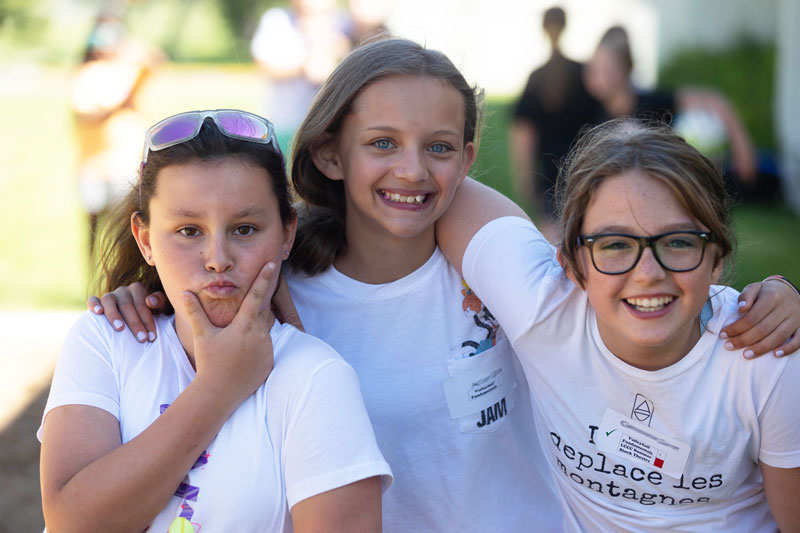 Three young students with arms around each other posing for the camera at the SEEK camp