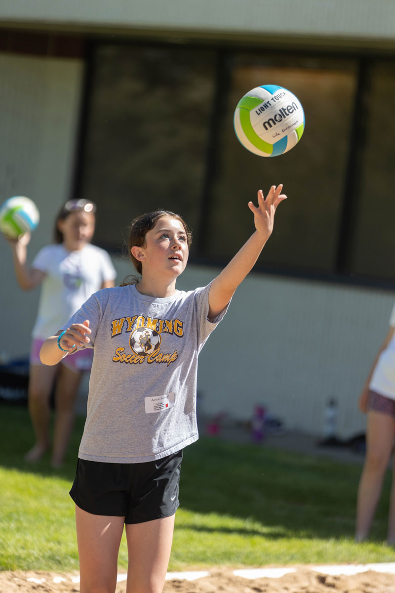 A student playing volleyball outside in sand in the SEEK class
