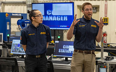 employees in the Advanced Manufacturing & Material Center talk about the new Smart SIM system behind them.