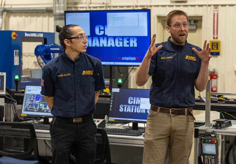 employees in the Advanced Manufacturing & Material Center talk about the new Smart SIM system behind them.