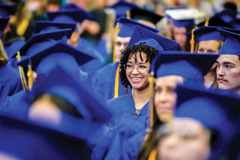 Students at LCCC Commencement in caps and gowns with one person in focus