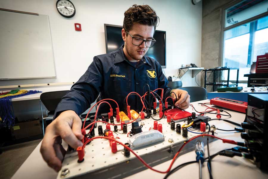 diesel tech student working on electronics with a board and wires.
