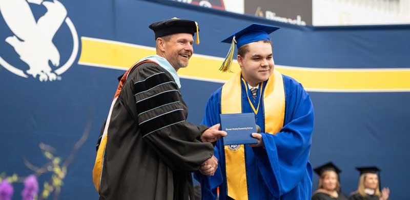 Caius Krupp shaking hands with Dr. Schaffer at commencement on stage