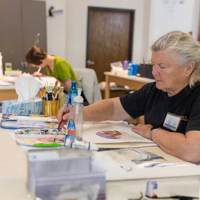 a student painting in the watercolor class