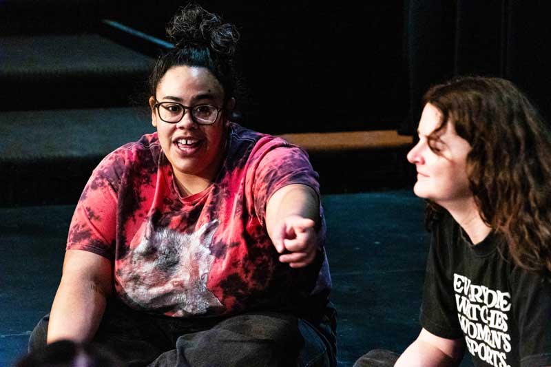 Two actors from Second City sitting on stage talking