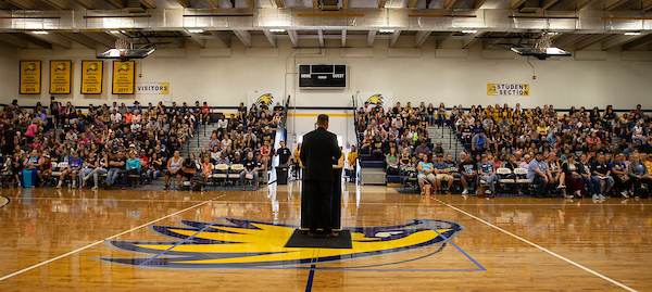 Joe addressing large group of students in gymnasium