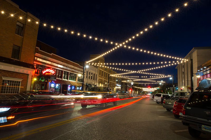 Photo of downtown street in Cheyenne with lights strung across the street and cars driving by