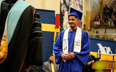 photo of a student at commencement walking across the stage in cap and gown