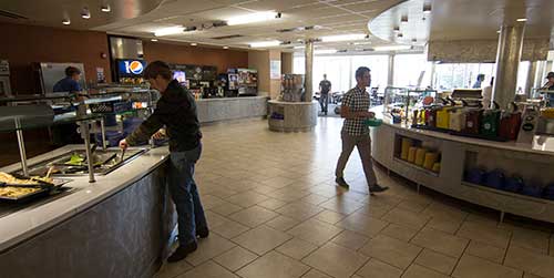 two students walking around the all you can eat buffet in the dining hall