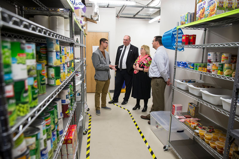 Donors and LCCC staff standing in the food pantry with the shelves of food