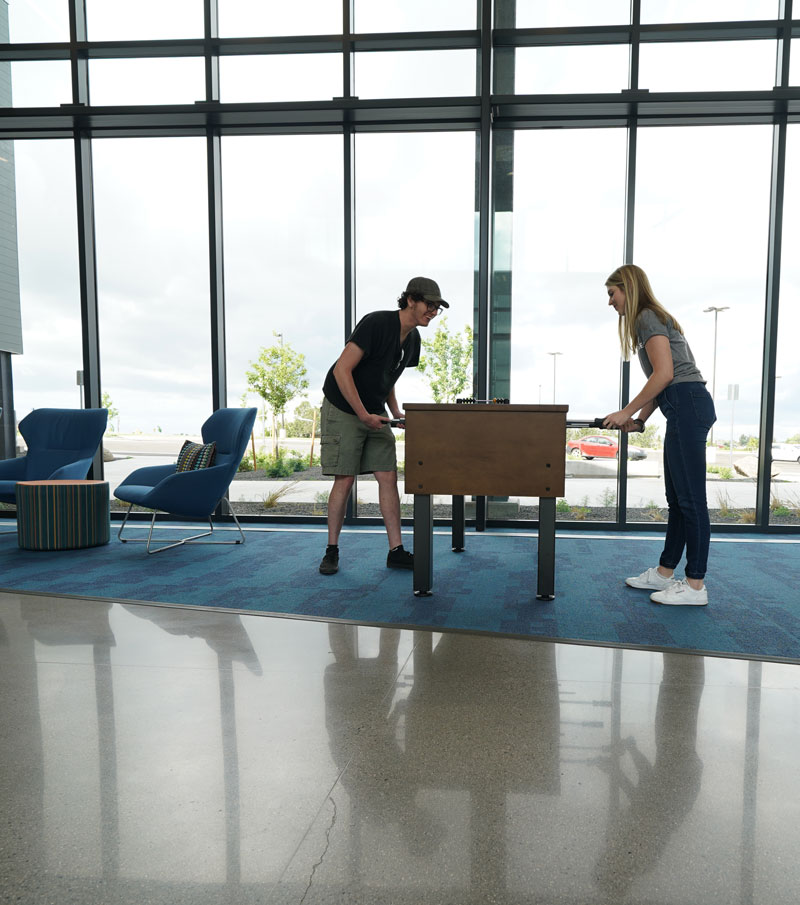 two students playing foosball in the lobby of Gold Hall