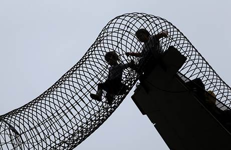 Two silhouetted children climb through an arch at the St. Louis City Museum 