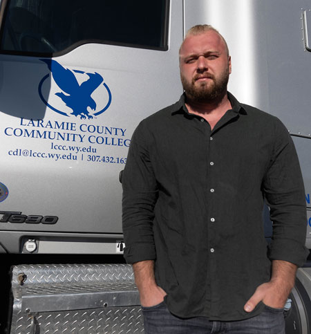 Photo of Olekdsandr Ageyev standing in front of an LCCC CDL semi truck