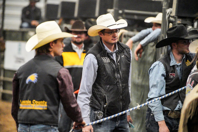 LCCC Rodeo Coach Seth Glause at a rodeo near the chutes by two students
