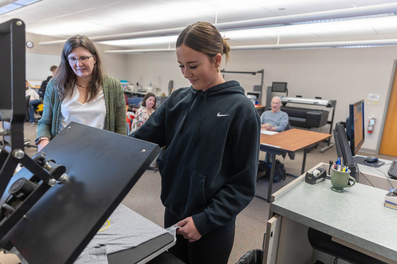 Minden Fox, LCCC marketing and business instructor, left, works with a student heat pressing a t-shirt in the Entrepreneurship Lab on the college's Cheyenne campus