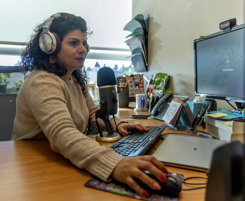 photo of Renee Nelson sitting at desk with microphone and headphones