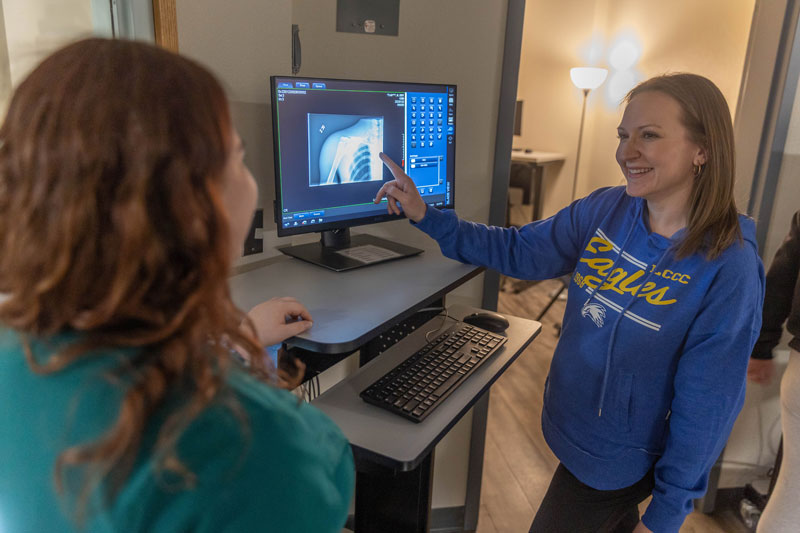 photo of Victoria Holmquist pointing to an x-ray on a screen