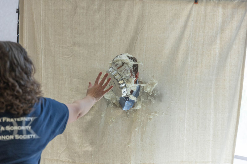 photo of the PTK pie throwing fundraiser with a person throwing a pie at another with their head stuck through a sheet.