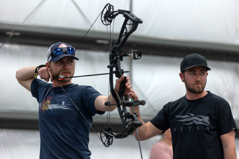 Photo of two students, one with a bow and arrow.