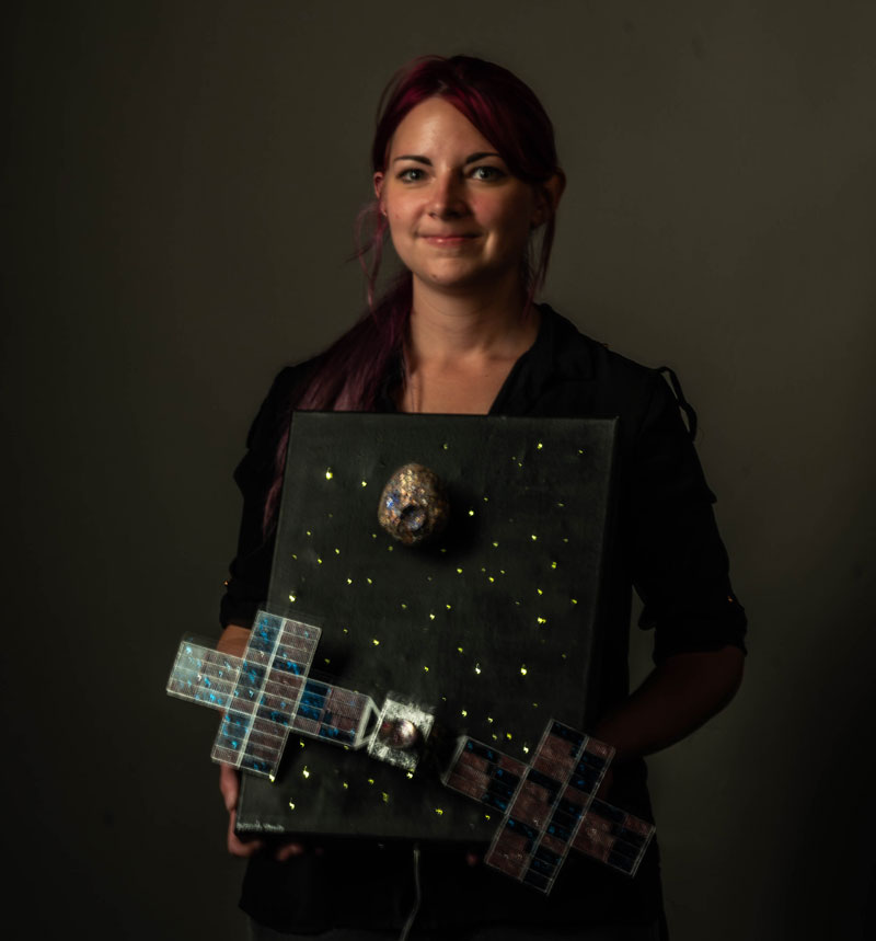 Miranda Unwin with artwork that looks like a satellite in space with a planet