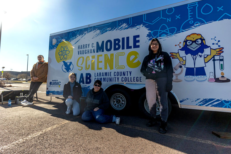 photo of four students standing next to the LCCC STEM trailer 
