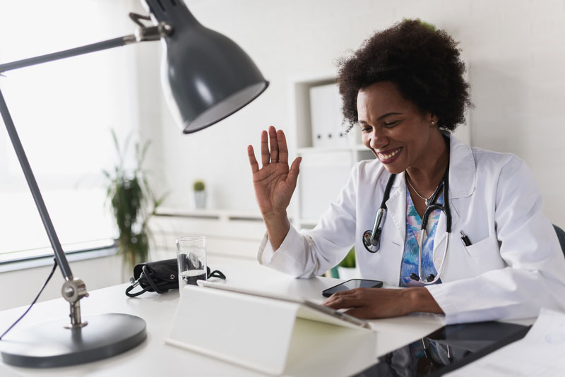 photo of a doctor talking to a tablet in her office and waving