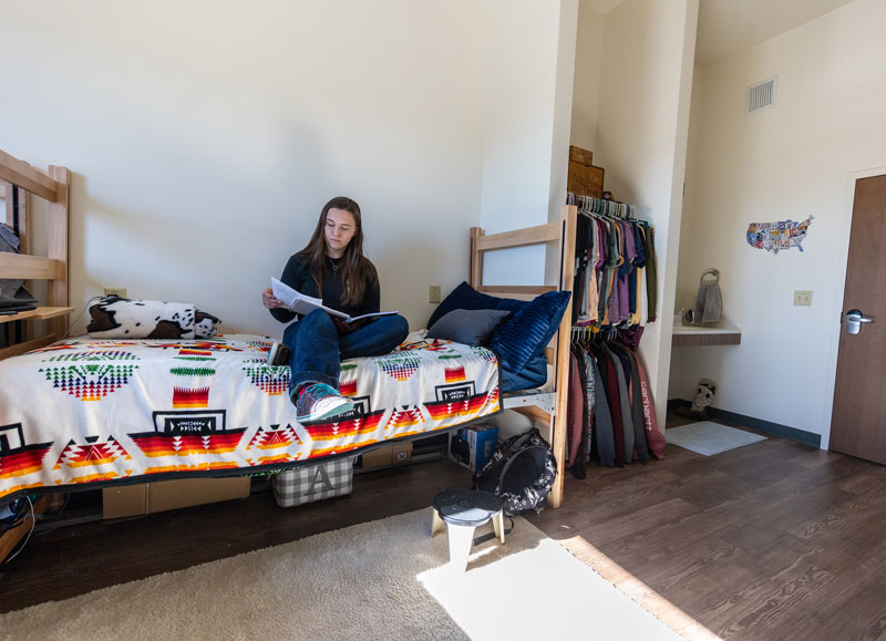 photo of student sitting on her bed in the Gold Hall residence hall