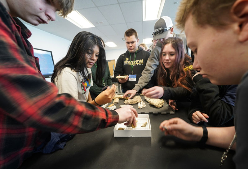 photo of a group of students looking at rocks on a tray