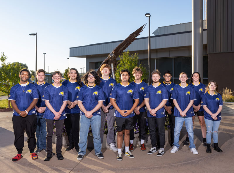 Photo of the entire Esports team standing outside by an eagle statue