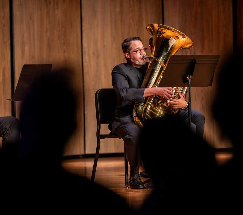 Faculty member playing the tuba on stage during a concert