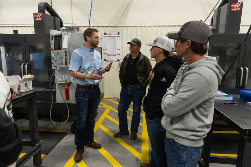 An AMMC instructor talking with people in the facility about the CNC machines.
