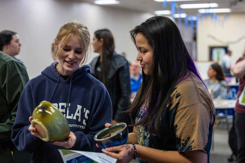 two students holding ceramic bowls