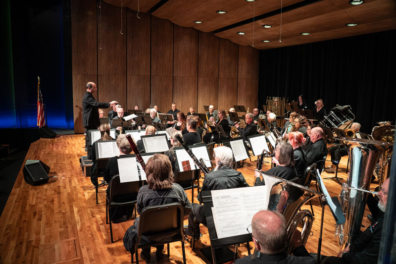 photo of musicians on stage with a conductor during a concert in the LCCC auditorium