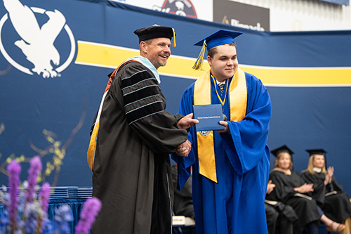 Caius Krupp accepts his dimploma cover from LCCC President Joe Schaffer