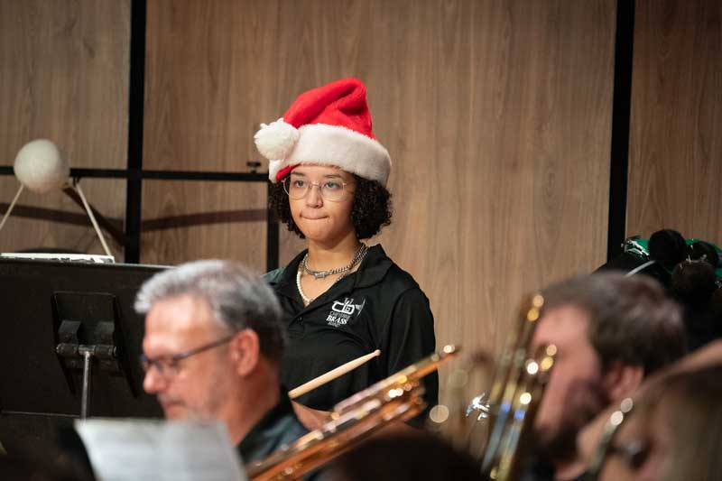 student musician playing drums on stage during a concert with a santa hat on