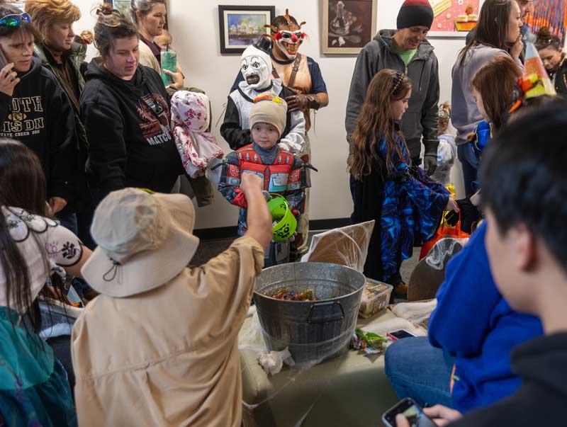 kids dressed up in Halloween costumes at the trunk or treat in the hallway at LCCC getting candy from a big bin
