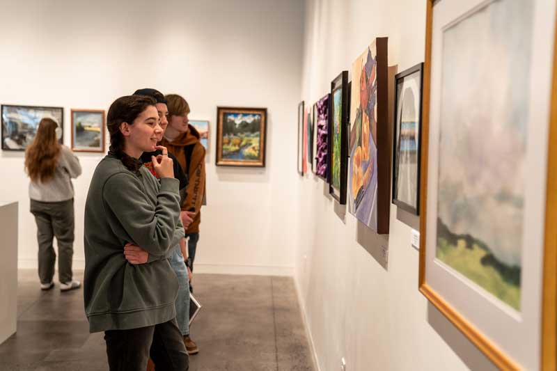 Students looking at artwork on the wall in the gallery.