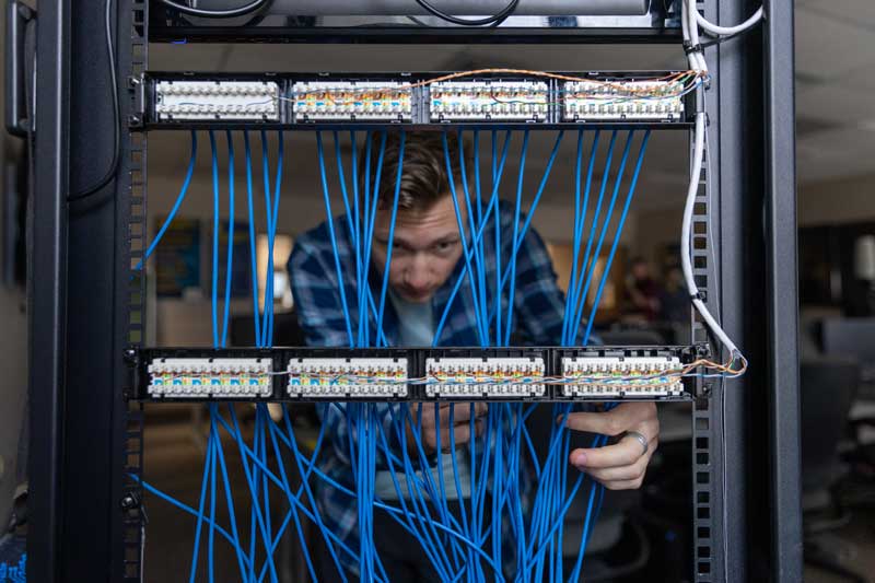 student holding onto bundles of cords as part of a network of computer components