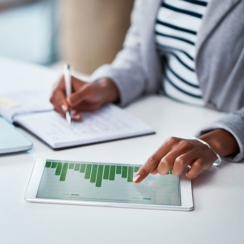 woman working on tablet with paper and pen