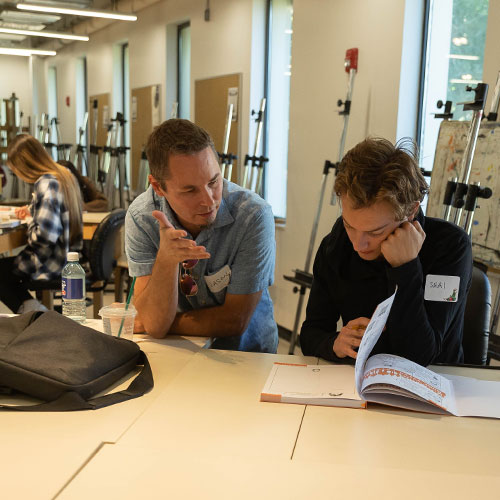 student in a classroom talking with an instructor