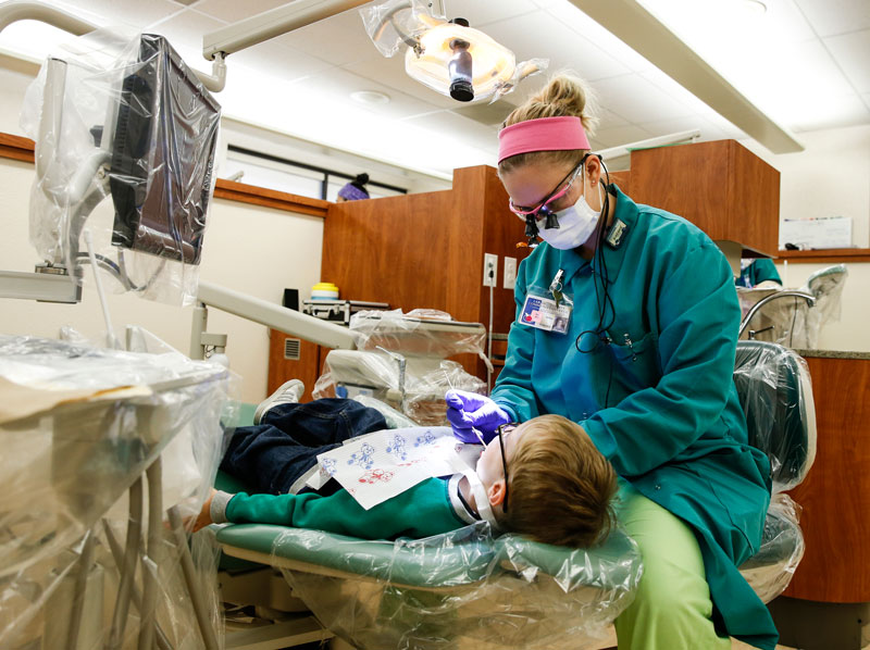 dental hygiene student cleaning child's teeth