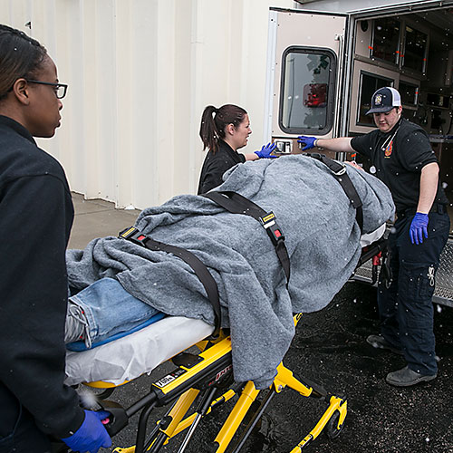 EMS students loading person on stretcher in ambulance